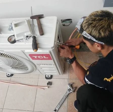 Technician servicing the connections of a compact outdoor air conditioning unit